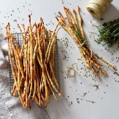 several different types of herbs on a wire rack next to twine spools