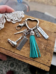 a close up of a person holding a keychain with scissors and combs on it