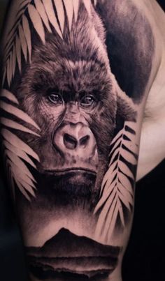 a man's arm with a gorilla and leaves tattoo on his arm, in black and grey