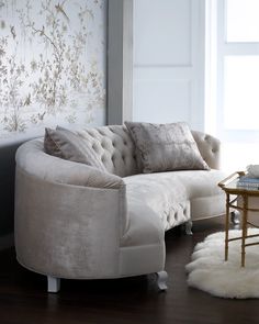 a white couch sitting on top of a hard wood floor next to a wall covered in flowers