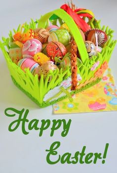 a green basket filled with lots of colorful easter eggs on top of a white table