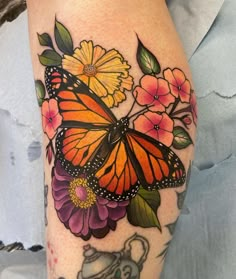 a butterfly and flowers tattoo on the leg