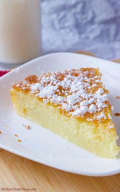 a piece of cake on a white plate next to a glass of milk