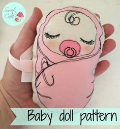 a hand holding a pink baby doll with eyes closed