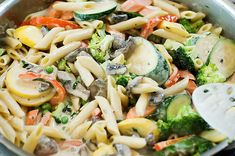 a pan filled with pasta and vegetables on top of a stove