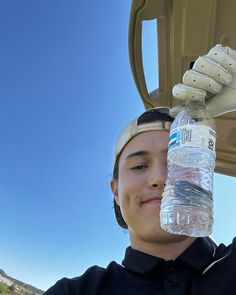 a young man holding a water bottle up to his face