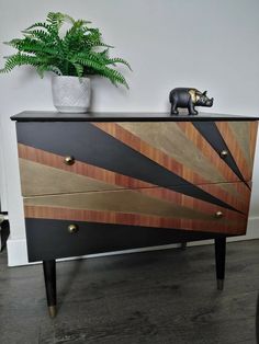 a black and gold chest of drawers next to a potted plant on top of it