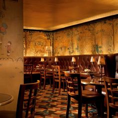 the interior of a restaurant with wooden tables and chairs, patterned wall paper on the walls