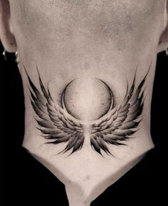 a man's neck with an angel wing tattoo on it and a ball in the center