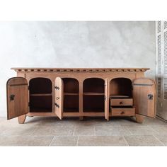 a wooden cabinet with two doors and drawers on the bottom, sitting in front of a wall