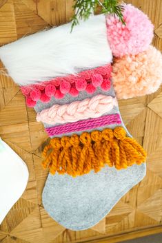 several different colored knitted stockings hanging on a wooden wall next to a potted plant