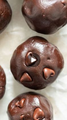 four chocolate donuts with faces on them