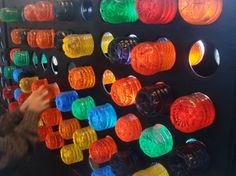 there is a man standing next to a wall with many different colored lights on it