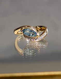 This one-of-a-kind RAPTURE ring embodies the beauty of harmony. It features a stunning and rare 1.20CT marquise cut teal sapphire from Montana, USA, set within our Demi Pavé RAPTURE design: an ocean-inspired silhouette with one side illuminated by shimmering white diamonds, creating an asymmetrical allure. A true modern heirloom that is artful yet timeless. The sublime sapphire exudes a gorgeous teal blue hue, calling to mind the the magical and dreamy ocean waters. To be in ‘rapture’ implies th Rapture Ring, Dreamy Ocean, Ring Inspo, Montana Usa, Teal Sapphire, Pearl Necklace Earrings, Ocean Inspired, Champagne Diamond, Engagement Ring Wedding Band