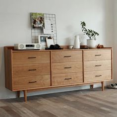 a wooden dresser sitting on top of a hard wood floor next to a white wall