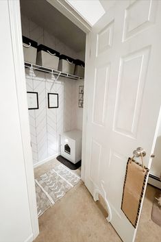 an open closet with white walls and black trim on the doors, has a cat litter box in it