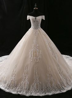 a wedding dress is displayed on a mannequin stand in front of a black background