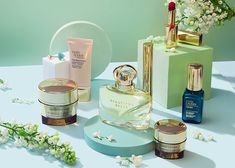 several different types of skin care products on a white table with flowers in the background