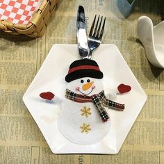 a white plate topped with a snowman sitting on top of a table next to a fork and knife