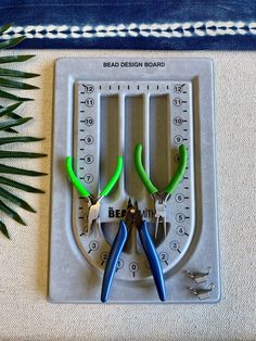 scissors and pliers are sitting on top of a board that is attached to a palm tree