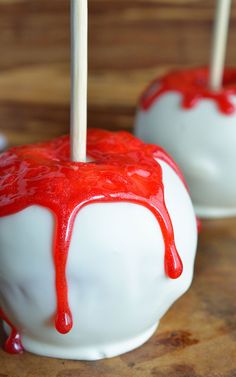 two caramel apples covered in white and red glaze with toothpicks sticking out of them