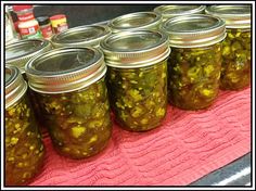 several jars filled with pickles sitting on top of a pink towel next to cans