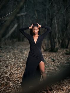 a woman in a black dress posing for the camera with her hands on her head