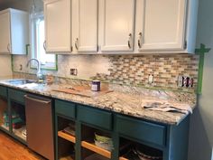 a kitchen with white cabinets and marble counter tops