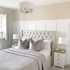 a bed with white headboard and pillows in a bedroom