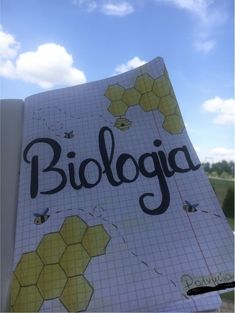 a notebook with the word biologia written on it in front of a blue sky