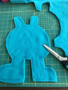 a pair of scissors sitting on top of a cutting mat next to a cut out piece of felt