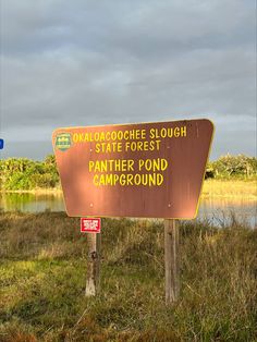 a sign that is in the grass by some water