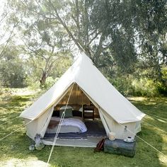 a tent with a bed in it on the grass