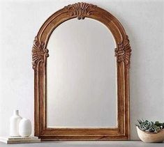 a mirror sitting on top of a table next to a vase and potted plant