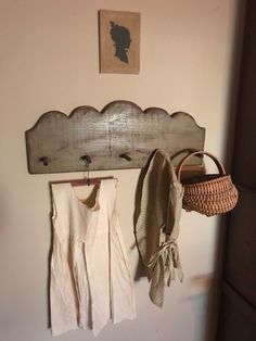 a wooden coat rack with two coats hanging on it's hooks and a basket next to it