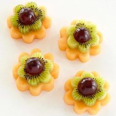 four pieces of fruit arranged in the shape of flowers on a white surface, including kiwis