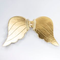 a gold leaf shaped brooch on a white background with clippings to the side