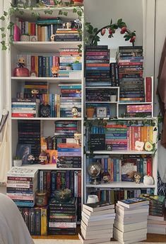 a bookshelf filled with lots of books next to a bed