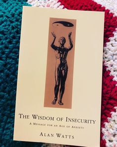 a book about the wisdom of insecity on a knitted blanket with an image of a man holding a disc above his head