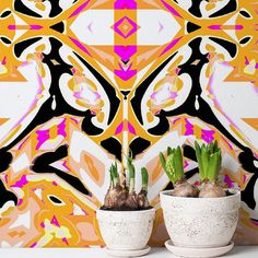 two potted plants sitting next to each other in front of a colorful wallpaper