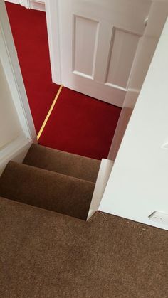 an open door leading to a red carpeted floor and white door with yellow trim