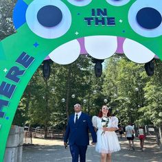 a man and woman are standing under an in the park sign with bubbles coming out of it