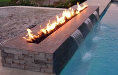 a fire pit sitting next to a swimming pool with water running down it's sides