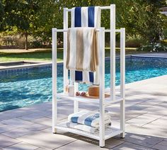 a towel rack next to a swimming pool with towels and other items on top of it