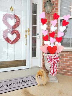 a small dog standing in front of a door with hearts on it's side