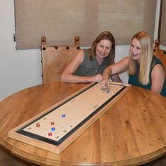 two women sitting at a table with a giant board game