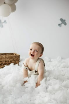 a baby is smiling while sitting in the clouds