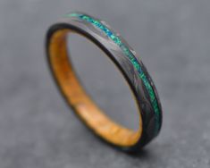 a wooden ring with green and blue inlays