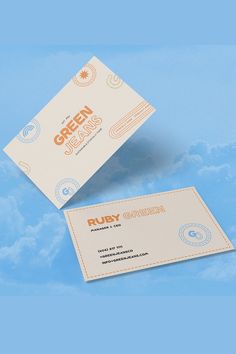 two business cards sitting on top of each other in front of a blue sky with clouds