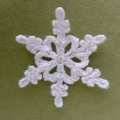 a white crocheted snowflake on a green surface